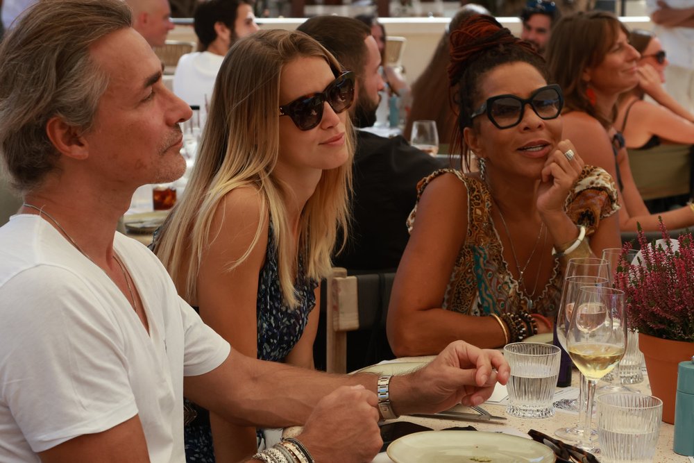 Guests at the seated lunch, food and wine on the table.