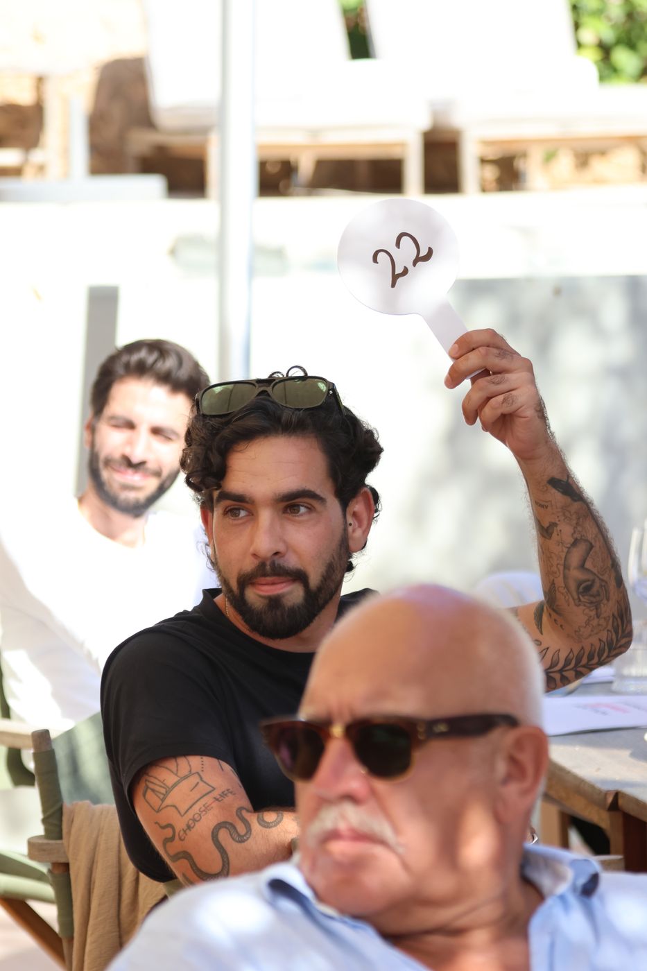 A guest in sunglasses raises bidding paddle 22 during the auction.